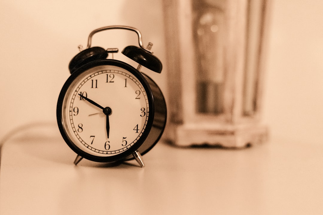 Vintage black alarm clock on a table with warm sepia tones