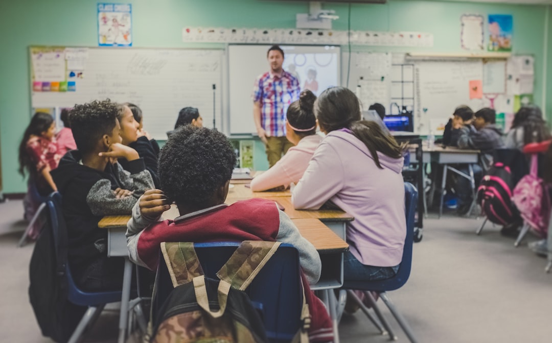 Teacher standing at the front of a classroom with students seated at desks