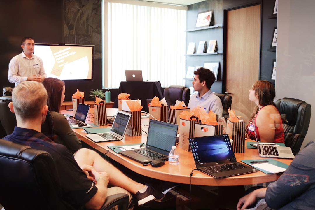 Presenter speaking to a group of people seated around a conference table with laptops